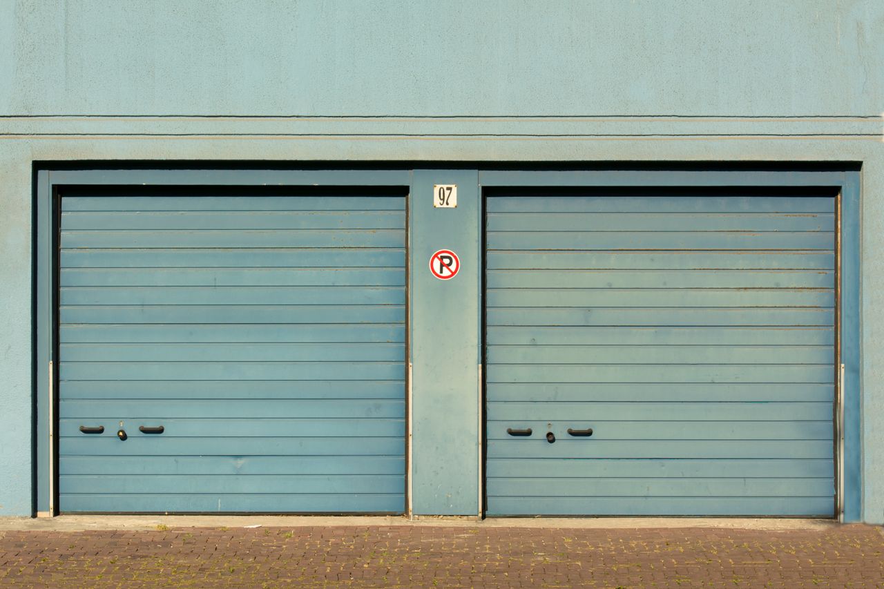 gallery-01 Blue garage doors with a no parking sign painted outdoors.